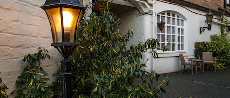 A traditional street lamp and a brick building with a white window and a hanging flower basket.
