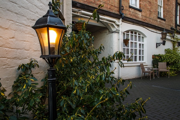 A traditional street lamp and a brick building with a white window and a hanging flower basket.