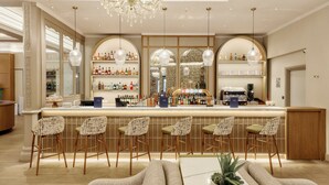 Un espace bar doté d’un long comptoir, de nombreux tabourets et d’un lustre.