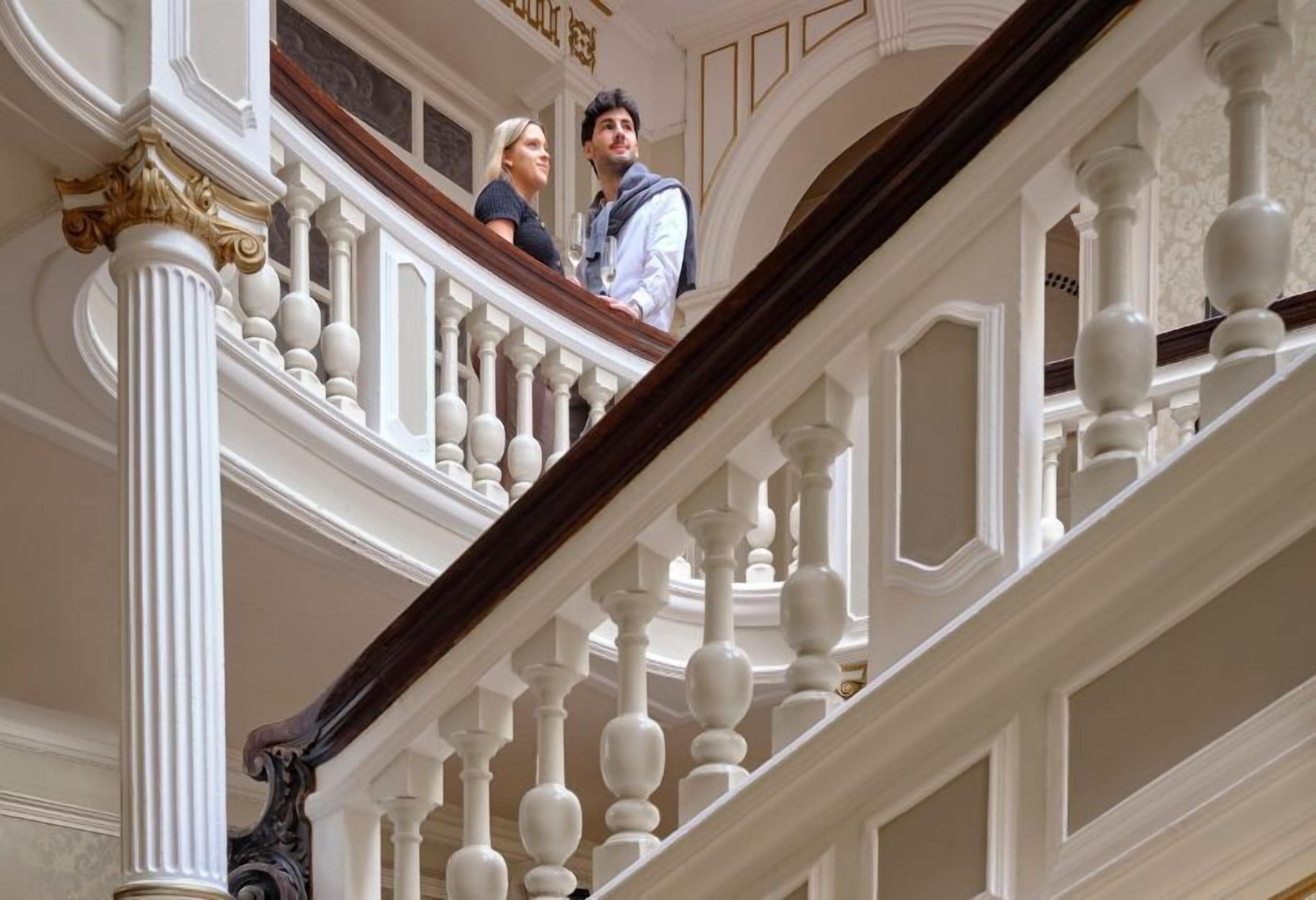 Una gran escalera con barandillas y columnas ornamentales, que conduce a un piso superior.