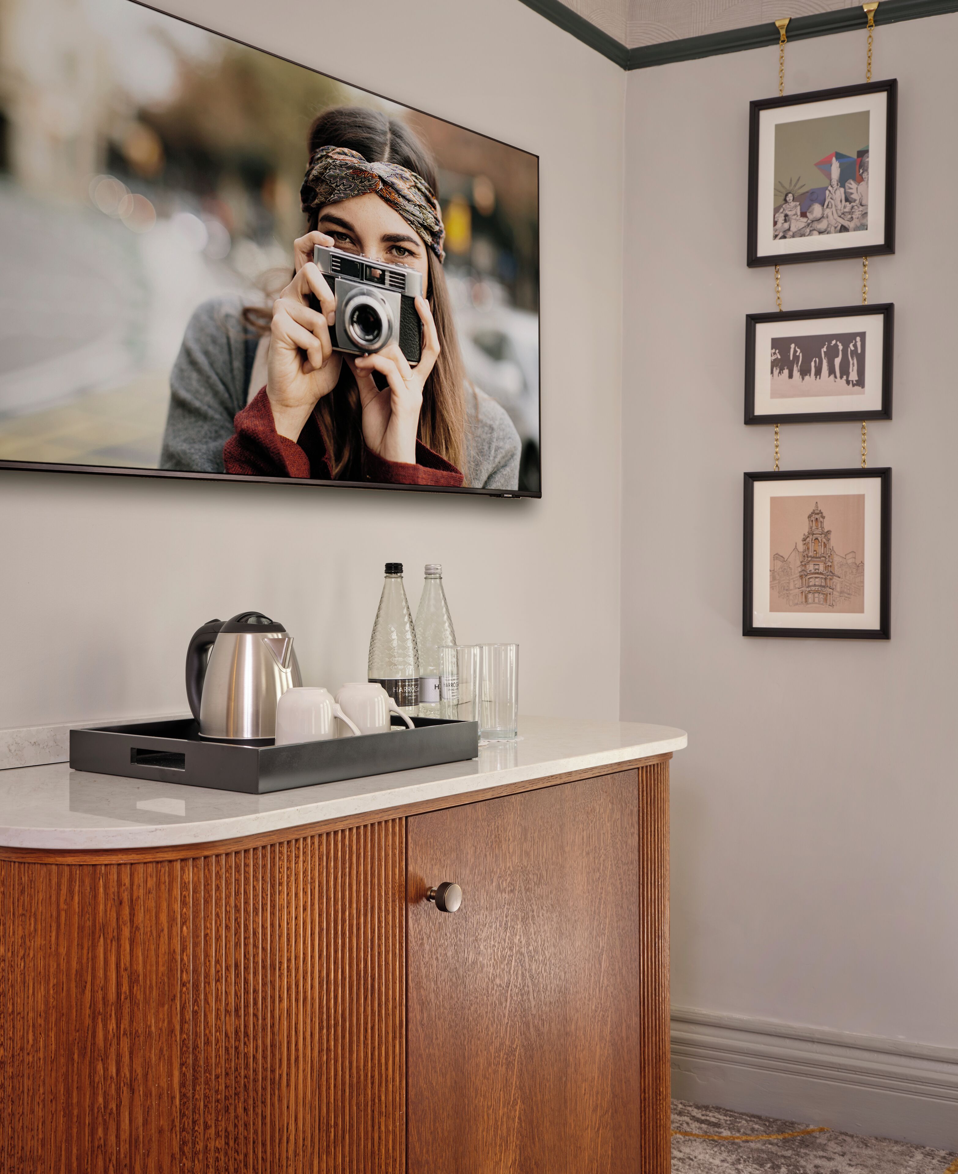 A modern bathroom with a wooden vanity, a mirror, and a framed photograph above the mirror.