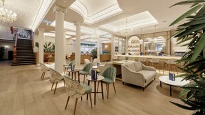 Un hall d’hôtel comprenant un bar, des espaces aménagés avec des sièges et un escalier.