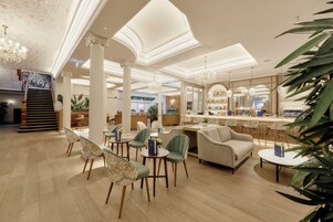 A hotel lobby with a bar area, seating arrangements, and a staircase.