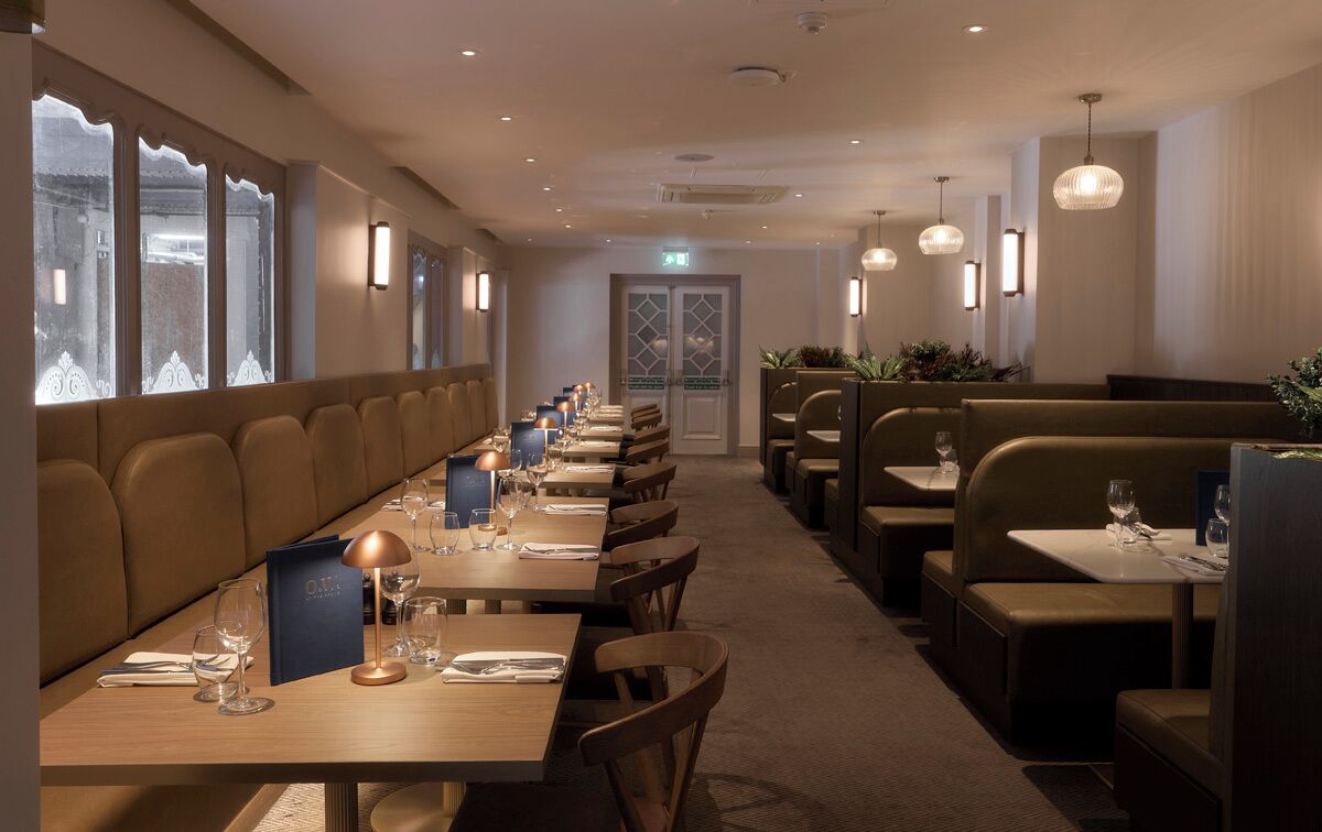 A restaurant with long tables, booths, and pendant lighting.