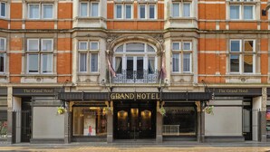 Une façade imposante, typique d’un grand hôtel, avec une conception symétrique, de grandes fenêtres et une entrée centrale.