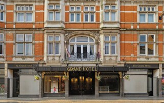 A grand hotel facade with a symmetrical design, large windows, and a central entrance.