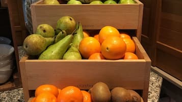 A wooden fruit crate filled with oranges, kiwis, and pears on a kitchen counter.