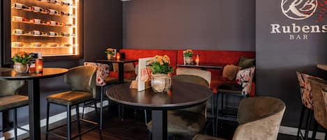 A bar area with round tables and chairs, a wall-mounted wine rack, and a sign reading "Rubens BAR".