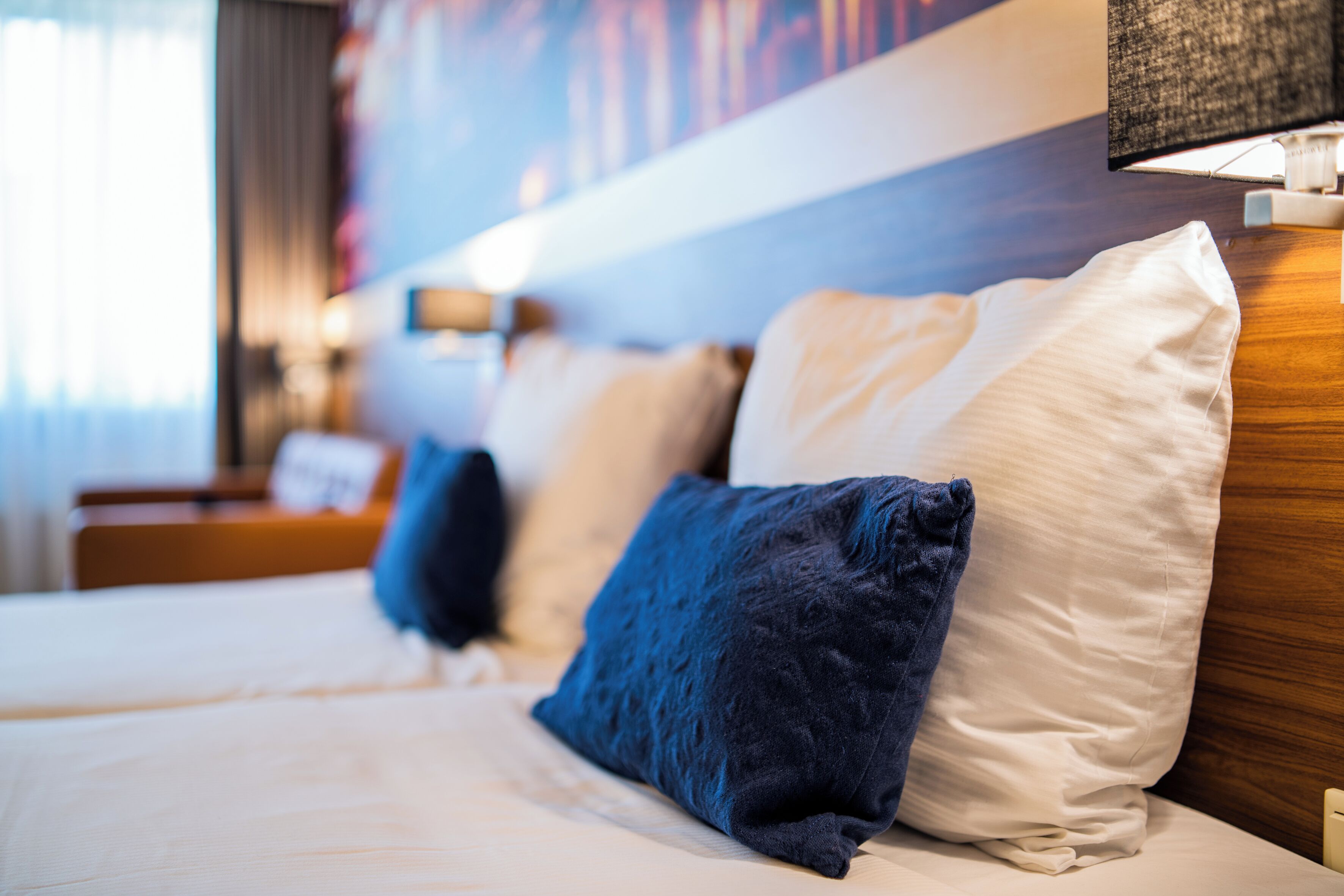 Habitació d'hotel amb llit, almoines, una taula de nit i una làmpada.