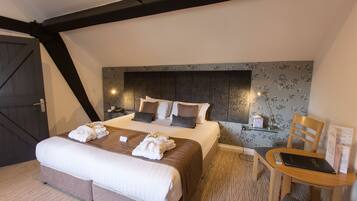A hotel room with a large bed, a wooden headboard, a bedside table with a lamp, a chair, and a small table with a remote control and a menu.