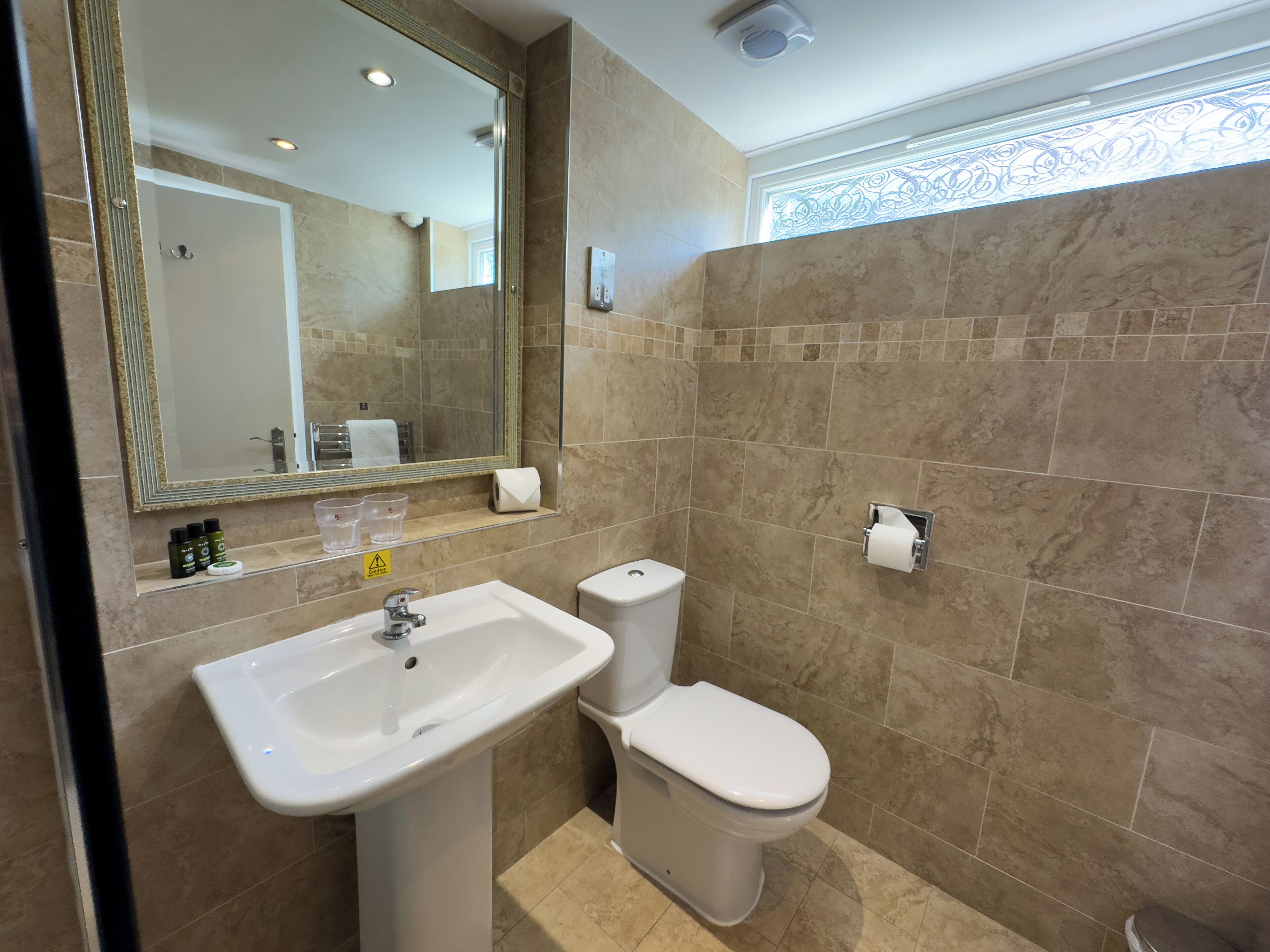Une salle de bain avec un lavabo, des toilettes et un miroir.
