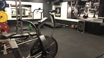 Un gimnasio con equipo de ejercicio, una cinta de correr y una pared decorada con carteles motivacionales.