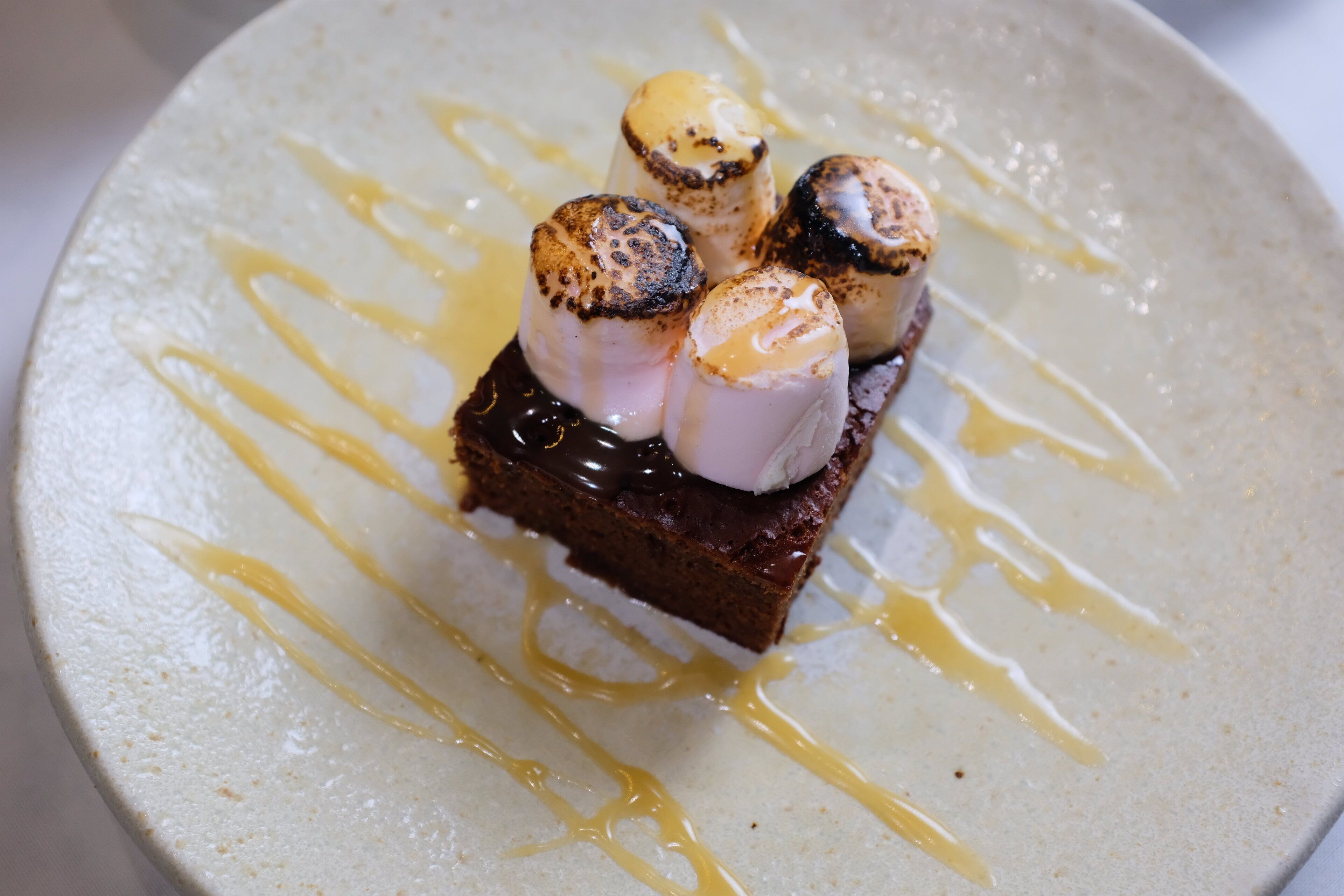 A dessert with marshmallows and chocolate sauce on a plate.