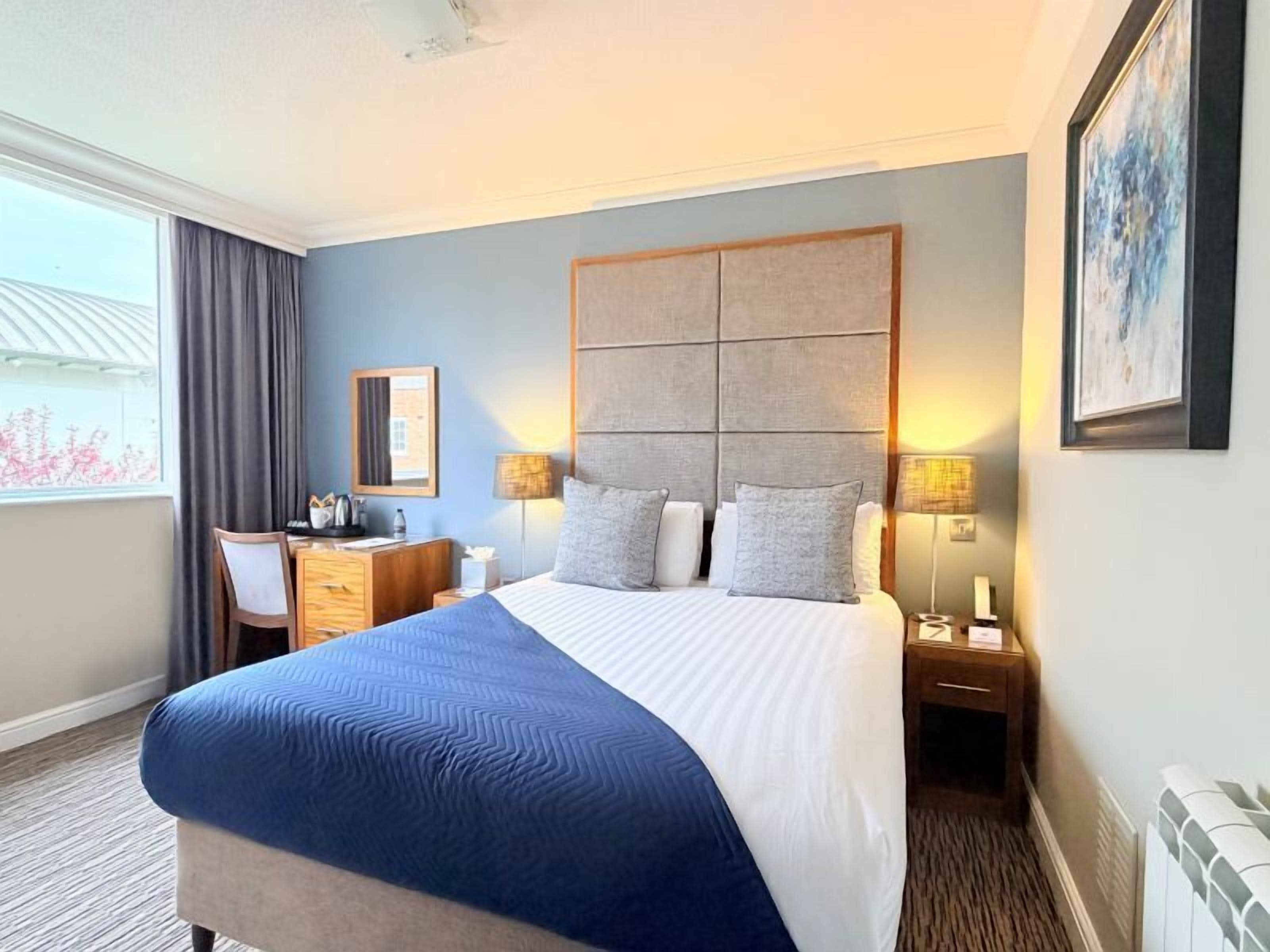 Une chambre d’hôtel avec un grand lit, un bureau, une chaise et une table de chevet.