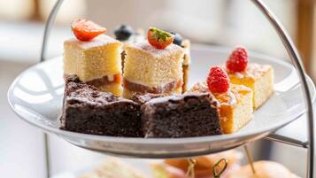 Una bandeja escalonada con diversos postres, incluyendo pasteles y brownies, adornada con fresas y arándanos.