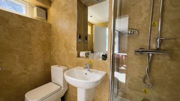 A modern bathroom with a toilet, sink, and glass-enclosed shower.