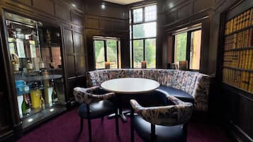 A room with a round table, two chairs, a bookshelf, and a glass display case.