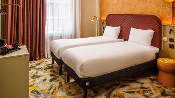 Une chambre d’hôtel avec deux lits, un bureau, une lampe et une moquette à motifs.