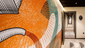Un pasillo de hotel con diseño moderno, que incluye un piso estampado y un gran mural en la pared.