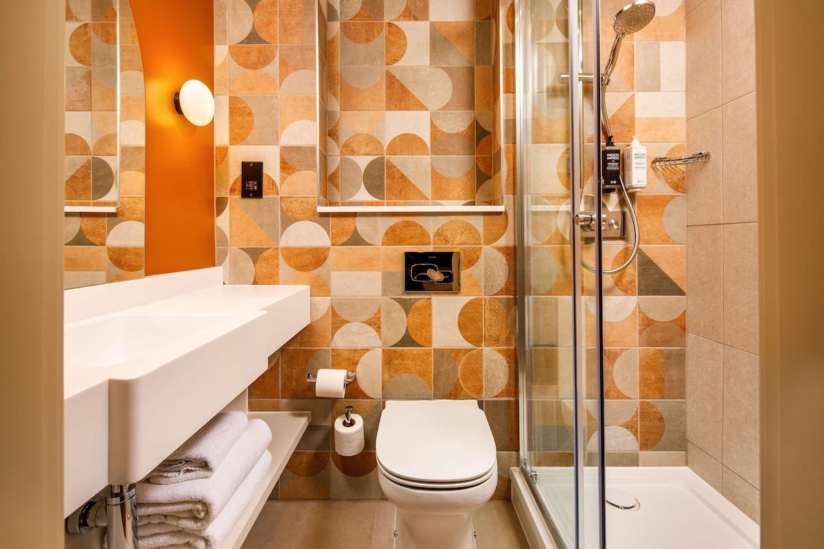 A modern bathroom with a shower, toilet, and sink.