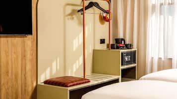 A hotel room with a bed, a wooden panel wall, a television, a minibar, and a window with curtains.
