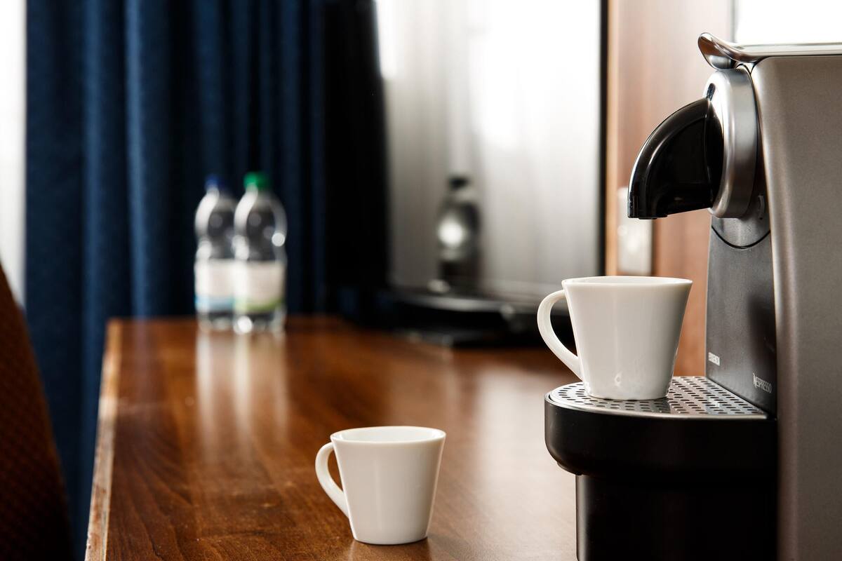 Une machine à café avec deux tasses blanches posées sur une table en bois.
