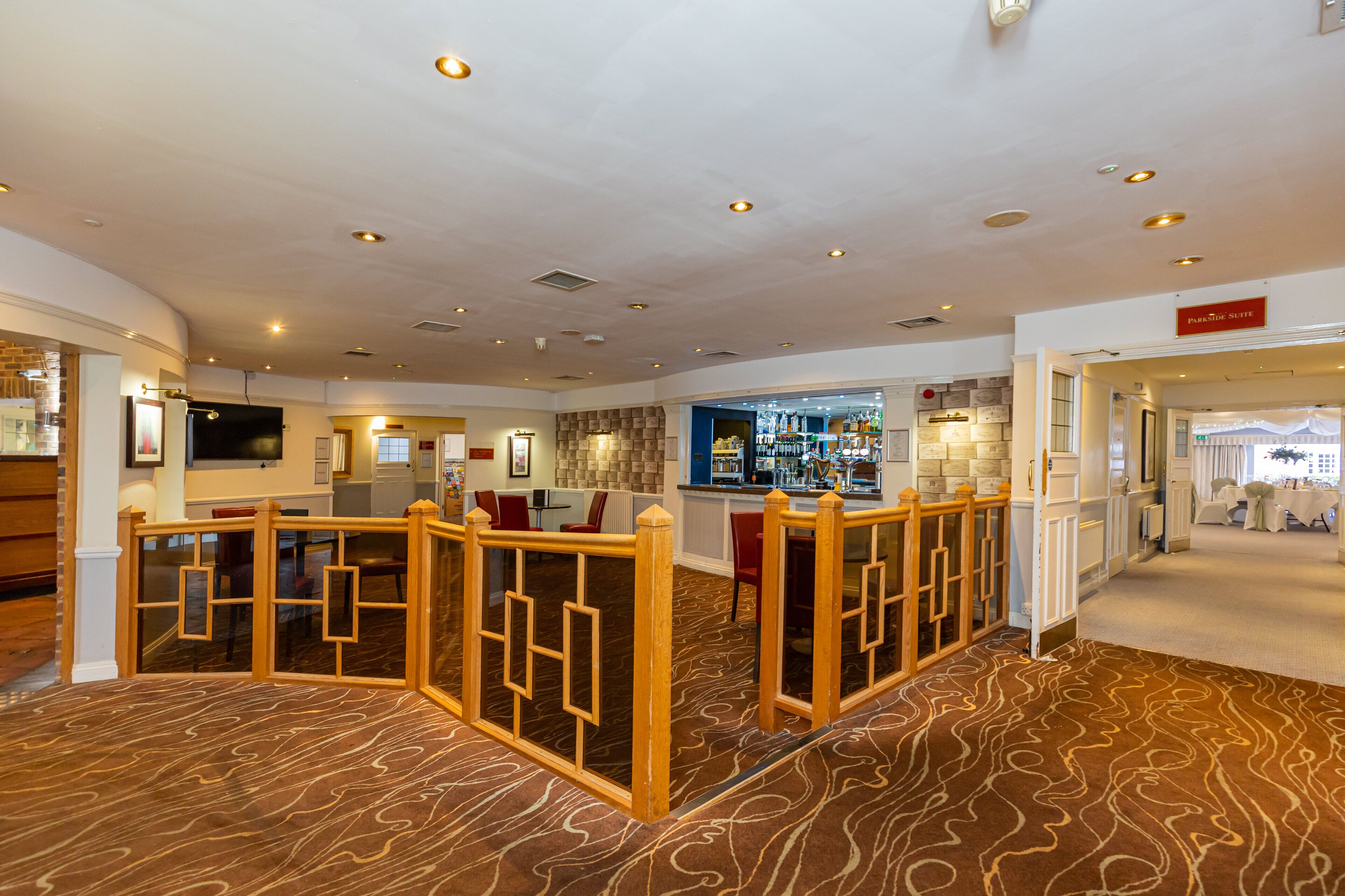 A hotel lobby with a bar area, seating, and a reception desk.