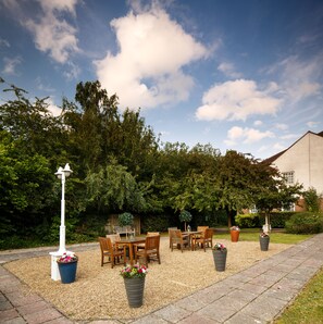 Relax in a serene outdoor seating area surrounded by lush greenery and potted flowers.