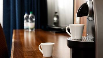 Una cafetera con dos tazas blancas sobre una mesa de madera.