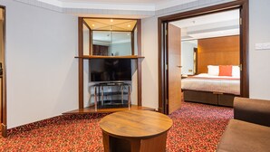 Une chambre d’hôtel avec un grand lit, une télévision, une table basse en bois et une moquette à motifs.