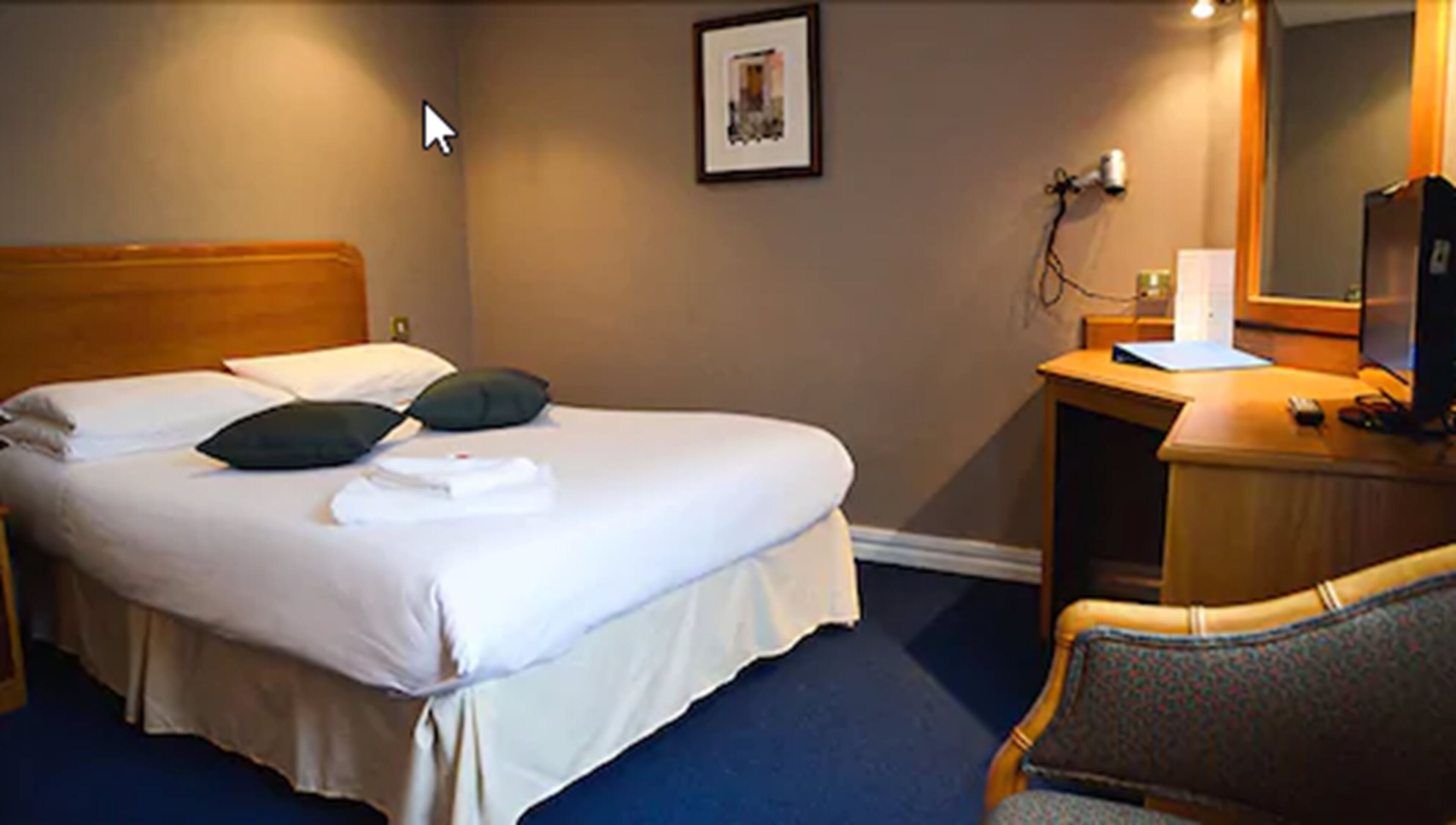 A hotel room with a bed, a desk, a chair, and a television.
