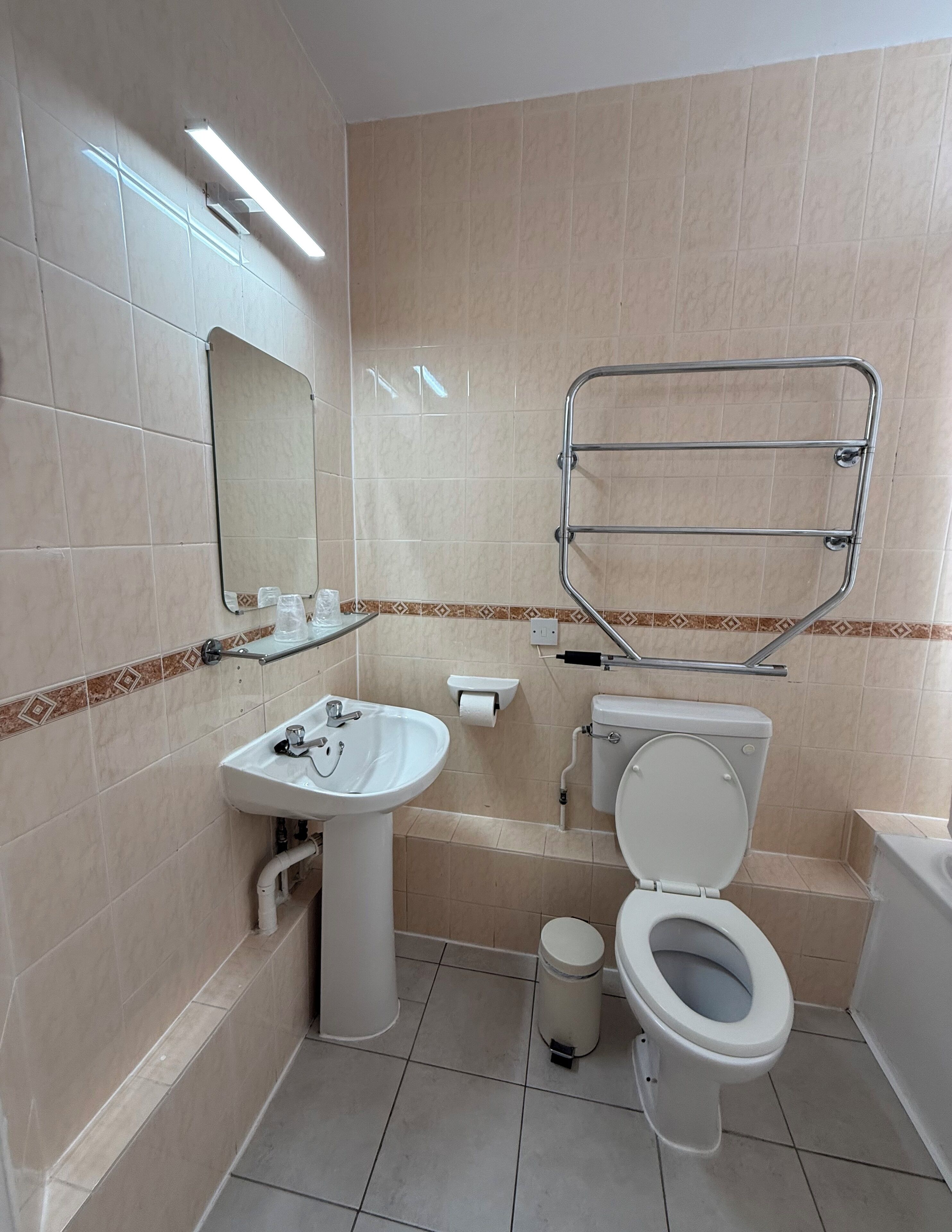 Un baño con lavamanos, inodoro y perchero para toallas.