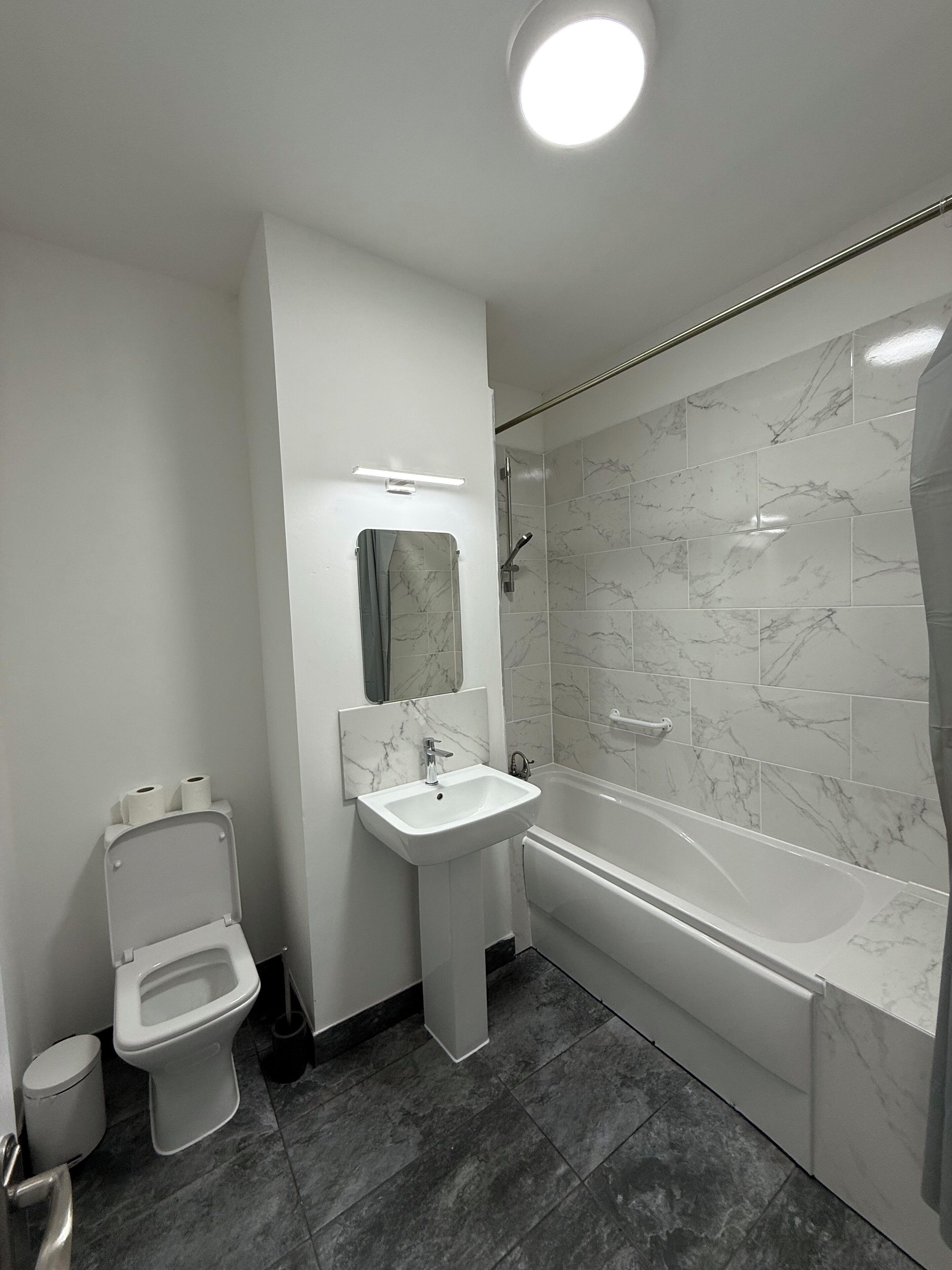 Une salle de bain moderne équipée de toilettes, d’un lavabo et d’une baignoire.