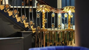 A staircase with ornate railings and a blue upholstered chair in the foreground. - Mercure Brighton Seafront Hotel (Brighton)