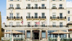 A multi-story hotel with a classic architectural style, featuring a prominent entrance, balconies, and flags. - Mercure Brighton Seafront Hotel (Brighton)