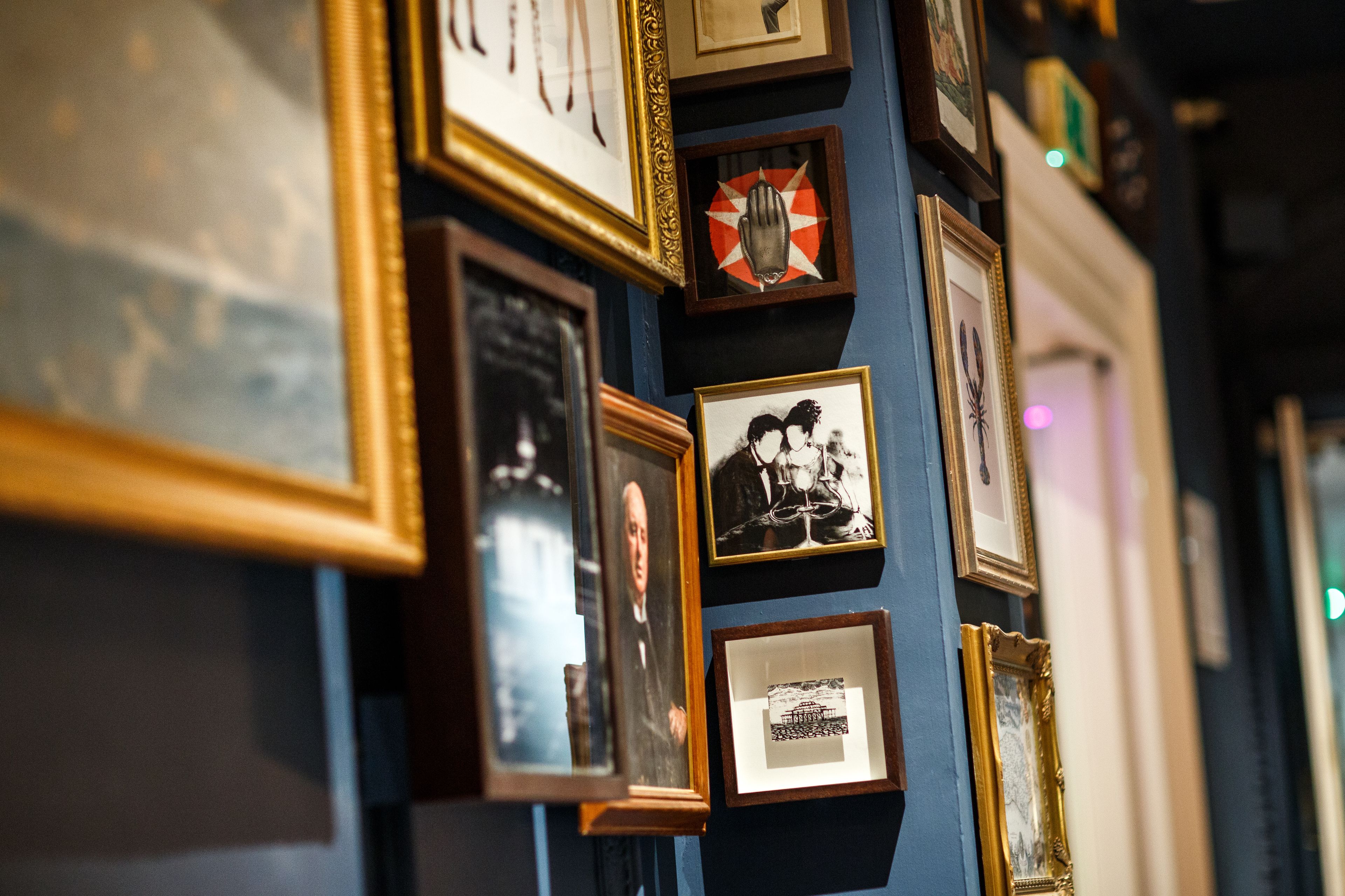 A wall with multiple framed photographs and artworks.