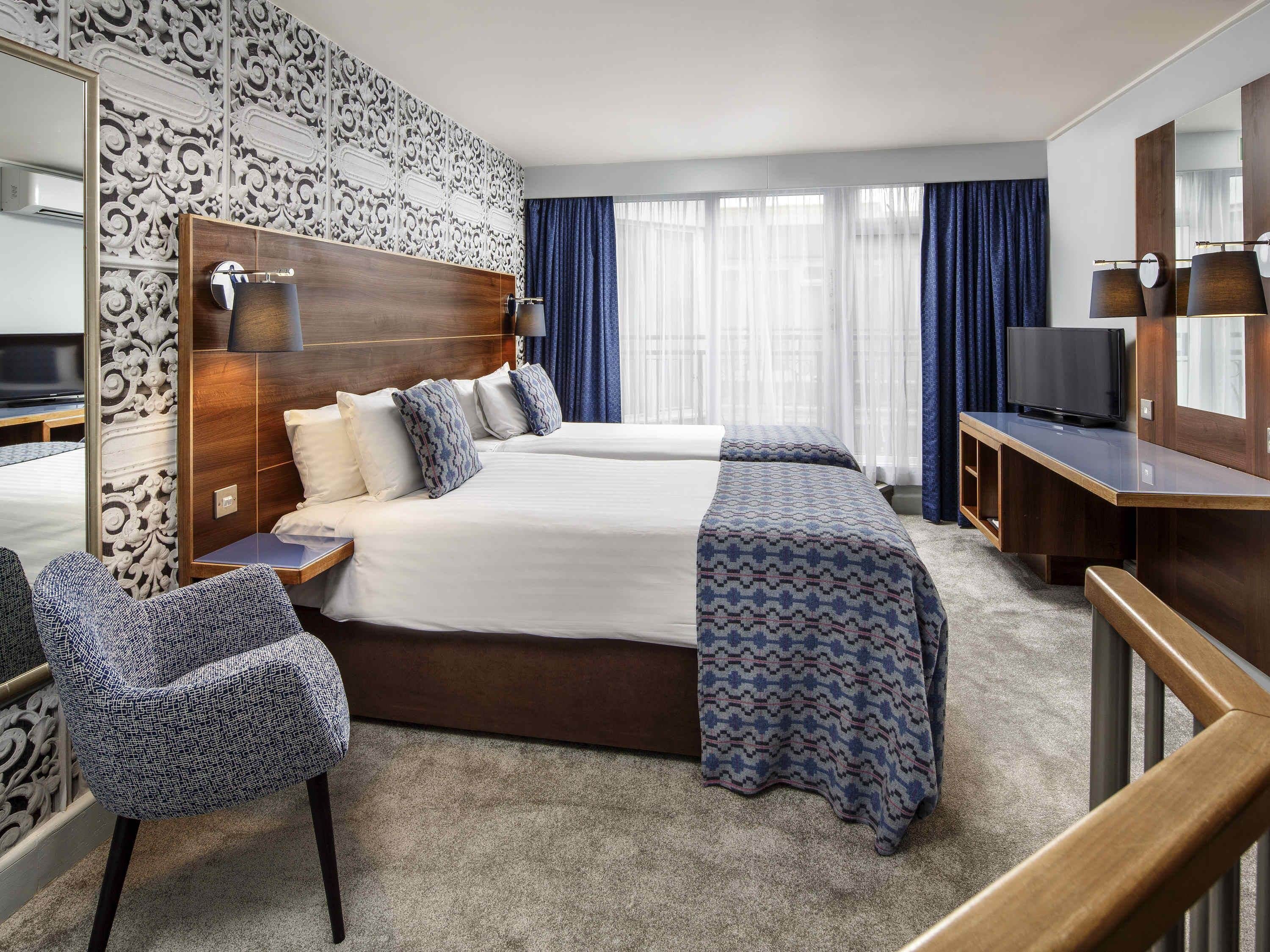 Une chambre d’hôtel avec un grand lit, une télévision, un bureau et une chaise.