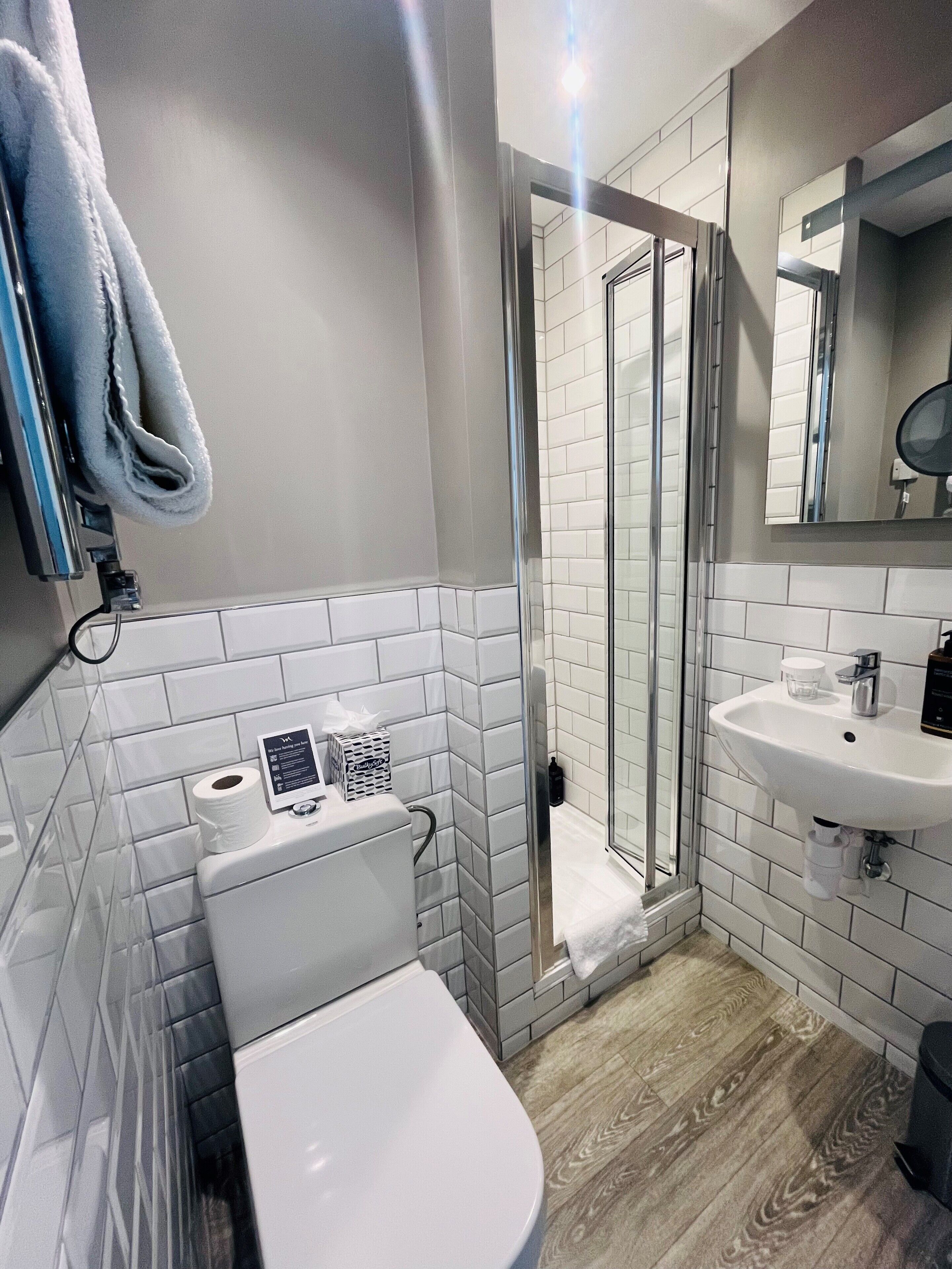 Une salle de bain moderne équipée de toilettes, d’un lavabo et d’une douche à parois en verre.
