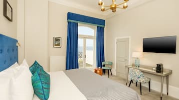 A hotel room with a bed, a desk, a chair, a TV, and a balcony view.