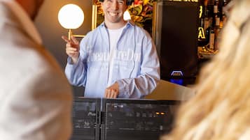 A person standing at a counter with a microphone, holding a light.