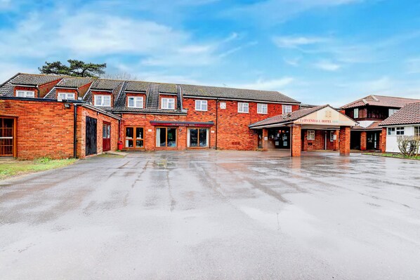 A large brick building with multiple entrances, likely a hotel, featuring a spacious courtyard.