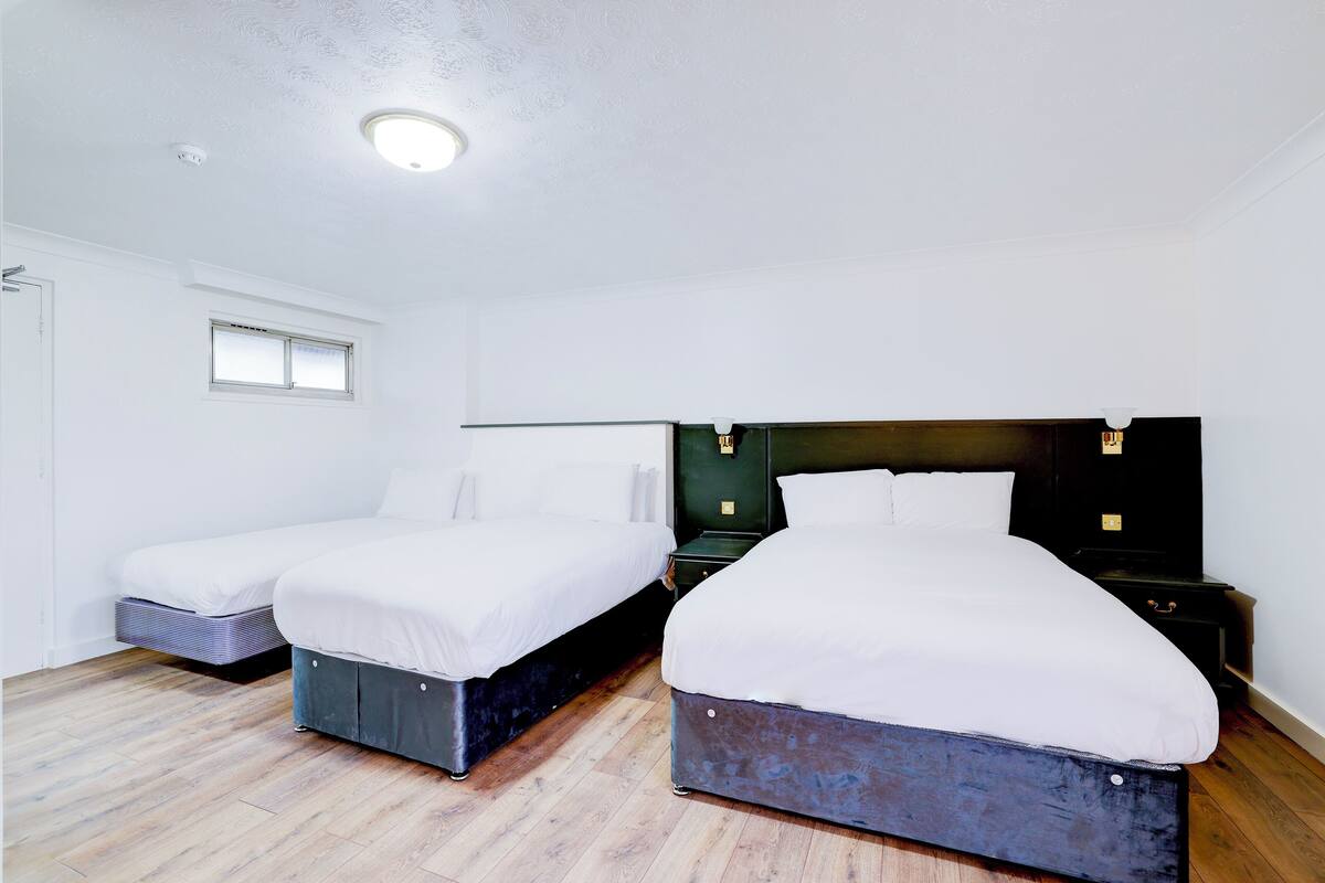 A bedroom with two beds, a window, and a ceiling light.