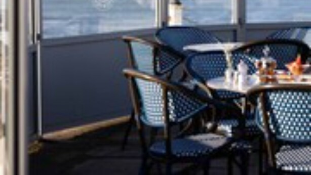 Un espace repas avec une table et des chaises, donnant sur un plan d’eau.