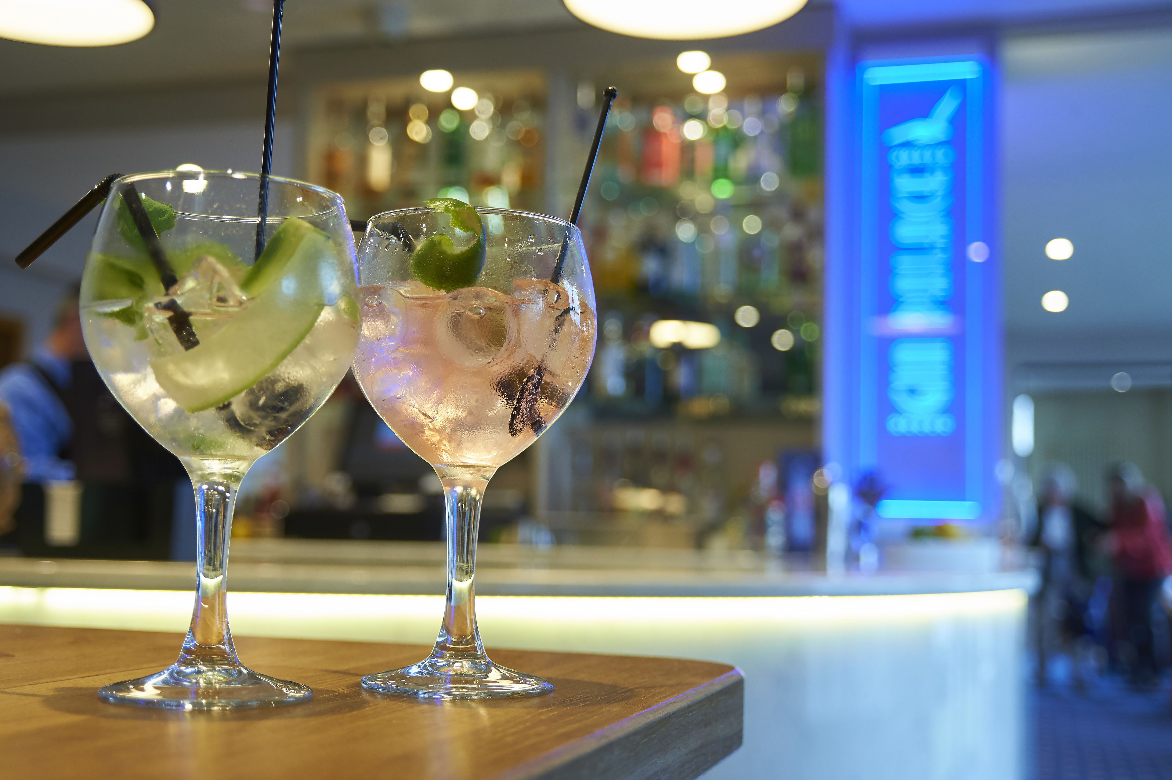Deux cocktails sur le comptoir d’un bar, avec un arrière-plan flou représentant le bar et les personnes qui s’y trouvent.