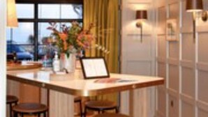 Un espace bar moderne comprenant un comptoir, des tabourets et un vase décoratif.