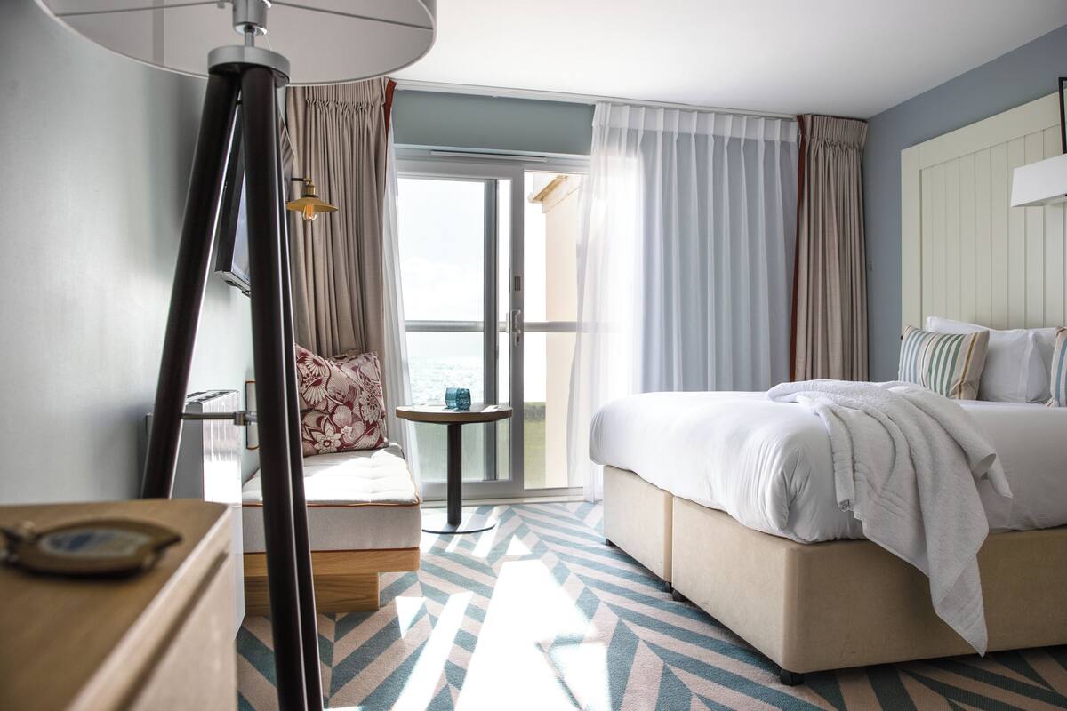 Een hotelkamer met een bed, een stoel, een tafeltje en een lamp.