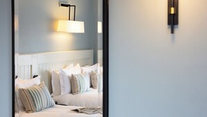Une chambre à coucher avec un lit, une table de chevet sur laquelle se trouve un verre, et une lampe fixée au mur.