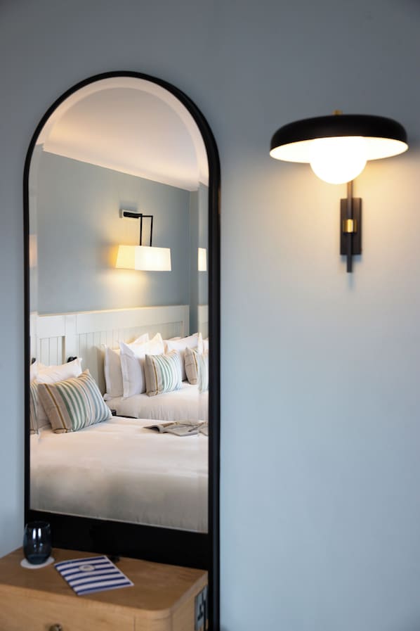 Un dormitorio con una cama, una mesita de noche con un vaso y una lámpara de pared.