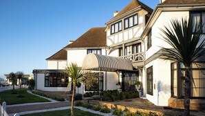 Une grande maison à deux étages, dotée d’un patio couvert, d’une pelouse bien entretenue et de diverses plantes.