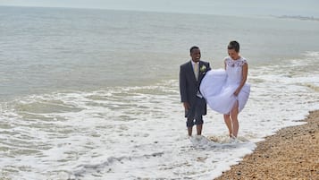 A couple standing on a beach with the sea in the background.
